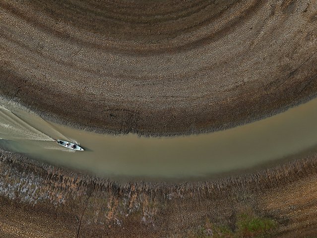 A drone view shows fishermen pushing an aluminium canoe to try to go fishing, in the middle of the dry bed of the Puraquequara lake caused by severe drought in the Amazon, in Manaus, Brazil on September 25, 2024. (Photo by Bruno Kelly/Reuters)