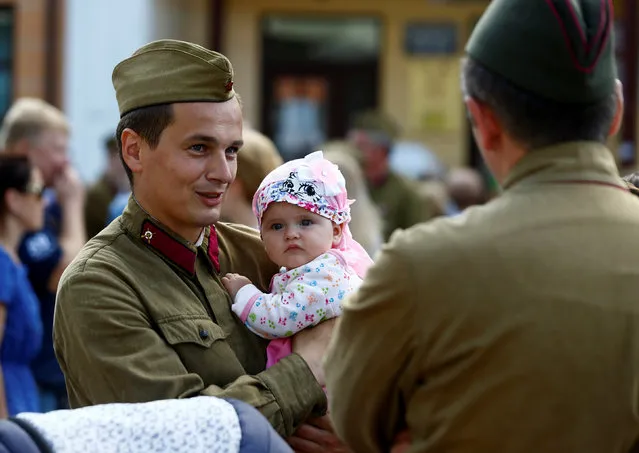 A military enthusiast dressed as  World War Two Red Army soldier holds his child as he marks the 75th anniversary of the Nazi Germany invasion, in Brest, Belarus June 21, 2016. (Photo by Vasily Fedosenko/Reuters)