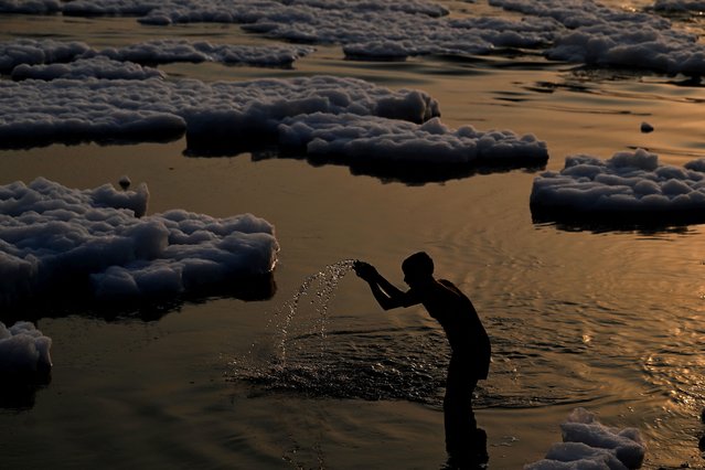 A man prays in the polluted waters of river Yamuna laden with foam, during sunrise in New Delhi on October 17, 2024. (Photo by Sajjad Hussain/AFP Photo)