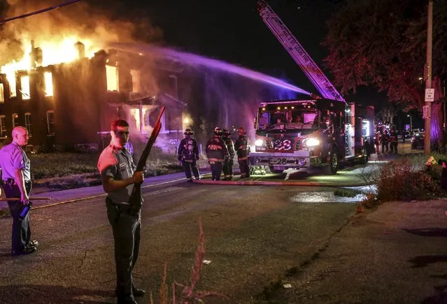 Firefighters attempt to put out a fire at an abandoned building with the protection of St. Louis City Police in St. Louis, Missouri August 19, 2015. (Photo by Lawrence Bryant/Reuters)
