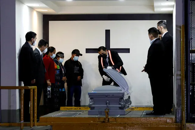 A funeral home employee opens the casket for the family of late migrant Juan Wilmer Tulul Tepaz, 14, following his repatriation after his death last month when he suffocated while being smuggled in a trailer in San Antonio, Texas, U.S., at La Aurora International Airport, in Guatemala City, Guatemala on July 16, 2022. (Photo by Luis Echeverria/Reuters)