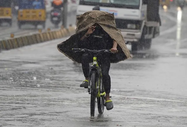 A man rides a cycle in the rain in Hyderabad, India, Friday, July 22, 2022. The monsoon season in India lasts from June to September. (Photo by Mahesh Kumar A./AP Photo)