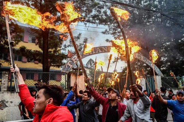 Student activists hold torches and shout slogans during a protest over hike in fuel prices in Kathmandu on June 20, 2022. (Photo by Prakash Mathema/AFP Photo)