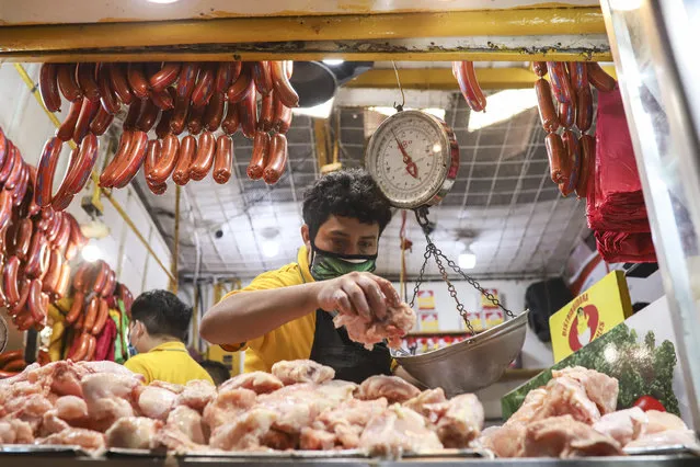 An employee weighs an order of chicken at a popular market in Managua, Nicaragua, Tuesday, April 7, 2020. (Photo by Alfredo Zuniga/AP Photo)