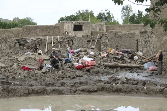 People collect their belongings from their damaged homes after heavy flooding in the Khushi district of Logar province south of Kabul, Afghanistan, Sunday, August 21, 2022. (Photo by Shafiullah Zwak/AP Photo)