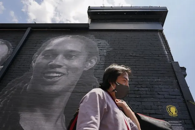 A visitor walks down an alley past a mural depicting WNBA star Brittney Griner, top left, and other American hostages and wrongful detainees who are being held abroad, Wednesday, July 20, 2022, in the Georgetown neighborhood of Washington. (Photo by Patrick Semansky/AP Photo)