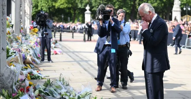 Britain's King Charles III looks at floral tributes left outside of Buckingham Palace in London, on September 9, 2022, a day after Queen Elizabeth II died at the age of 96. Queen Elizabeth II, the longest-serving monarch in British history and an icon instantly recognisable to billions of people around the world, died at her Scottish Highland retreat on September 8. (Photo by Daniel Leal/AFP Photo)
