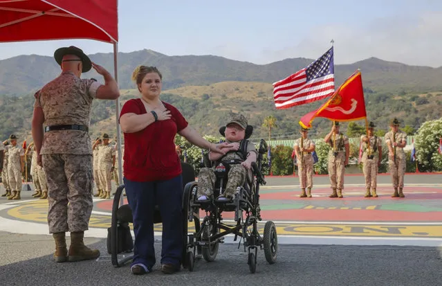 Wyatt Gillette, 8, front right, visits Camp Pendleton, Calif., Saturday, July 30, 2016, with his mother Felicia, front center, as his father, Marine Staff Sgt. Jeremiah Gillette salutes during a ceremony where the young Gillette received an award to become an honorary Marine. Gillette, who had the genetic disease Aicardi-Goutieres syndrome, which causes seizures and kidney failure, died Sunday, July 31, 2016. (Photo by Lance Cpl. Angelica Annastas/U.S. Marine Corps via AP Photo)