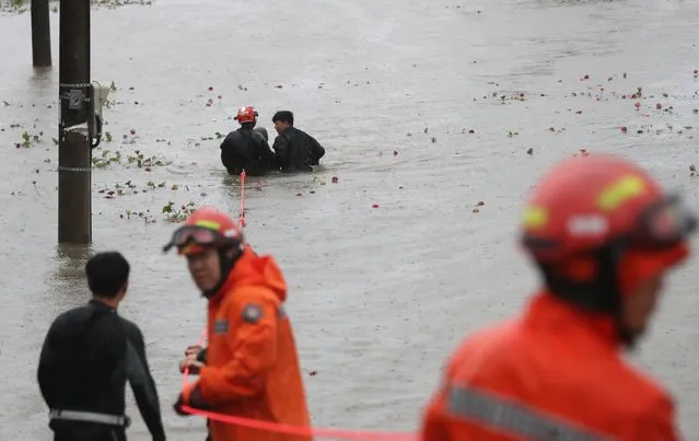 South Korean rescue workers rescue a man from a flooded riverside park in Ulsan on September 6, 2022, as Typhoon Hinnamnor hit South Korea's southern provinces. (Photo by Jung Yeon-je/ Yonhap via AFP Photo)