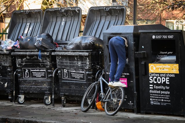 A man balances on a bicycle as he searches inside a electrical item recycling bin for valuables on November 28, 2023 in London, United Kingdom. A poll has found that £3.2bn of charity donations are potentially at risk due to the ongoing cost of living crisis. The results suggest that 25% of the public will give less to charity this Christmas, as they attempt to manage their own household budget. (Photo by Leon Neal/Getty Images)