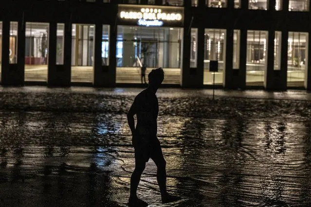 A man walks through a flooded street in front of a hotel powered by an oil generator during a blackout in Havana, Cuba, Wednesday, September 28, 2022. (Photo by Ramon Espinosa/AP Photo)