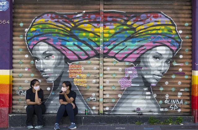 Women talk outside a closed outfit store during a quarantine imposed by the state government to help contain the spread of the new coronavirus in Sao Paulo, Brazil, Monday, June 1, 2020. (Photo by Andre Penner/AP Photo)