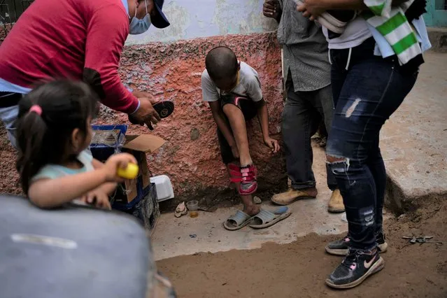 Victor Avila tries on pair of sneakers given to him after he survived a landslide that ripped through Las Tejerias, Venezuela, Tuesday, October 11, 2022. Rescuers worked to clear rocks and mud from the streets, three days after the massive and deadly landslide, and expanded their search for any bodies buried under the sludge. (Photo by Matias Delacroix/AP Photo)