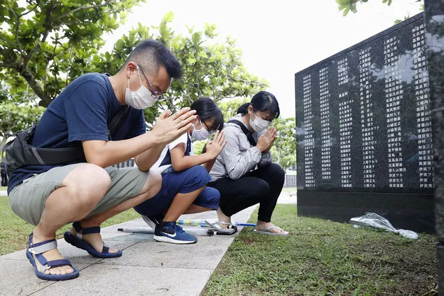 Members of a bereaved family pray in front of a “Cornerstone of Peace” monument wall on which the names of all those who lost their lives, both civilians and military of all nationalities in the Battle of Okinawa are engraved, at the Peace Memorial Park in Itoman, Okinawa, Japan, Tuesday, June 23, 2020. Okinawan people find it unacceptable that their land is still occupied by a heavy U.S. military presence even 75 years after World War II. They have asked the central government to do more to reduce their burden, and Japanese Prime Minister Shinzo Abe's government repeatedly say it is mindful of their feelings, but the changes are slow to come. (Photo by Kyodo News via AP Photo)