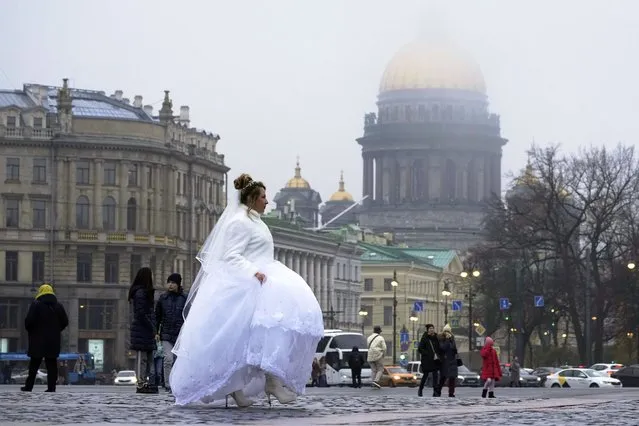 A bride walks at the Palace Square in St. Petersburg, Russia, Tuesday, November 1, 2022. (Photo by Dmitri Lovetsky/AP Photo)