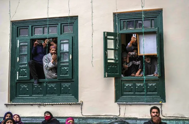 Kashmiri Muslim devotees pray from the windows of a mosque as a priest displays a relic of Sufi saint Sheikh Syed Abdul Qadir Jeelani outside his shrine in Srinagar, Indian controlled Kashmir, Monday, November 7, 2022. Hundreds of devotees have gathered at the shrine for the 11-day festival that marks the death anniversary of the Sufi saint. (Photo by Mukhtar Khan/AP Photo)