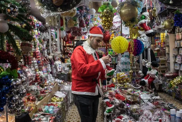 A store employee dressed in a Santa suit prepares items for sale at a shop selling Christmas decorations on December 20, 2017 in Istanbul, Turkey. Some luxury brands, shopping malls and retail outlets promote Christmas in an attempt to attract customers despite Turkey having a 98% Muslim population. (Photo by Chris McGrath/Getty Images)