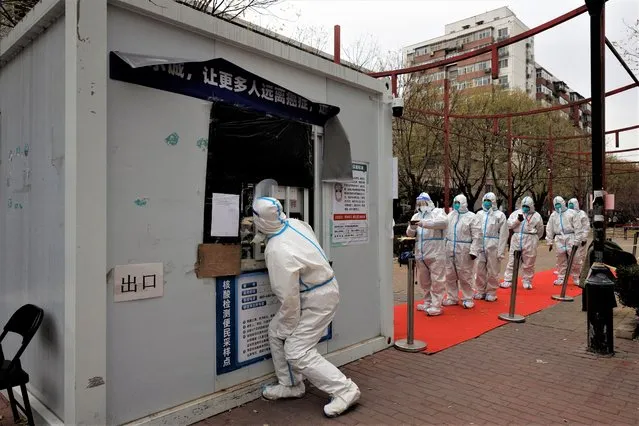 Epidemic-prevention workers in protective suits line up to get swab tested as outbreaks of coronavirus disease (COVID-19) continue in Beijing, China on November 28, 2022. (Photo by Thomas Peter/Reuters)