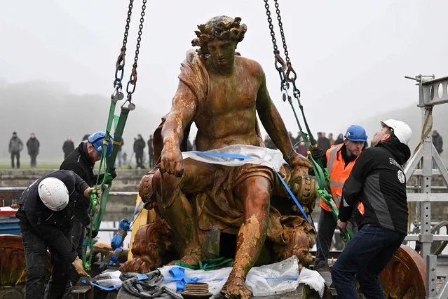 The sculpted group Apollo on his Chariot is hooked before being lifted as part of the launch of the restoration of the basin of the Chariot of Appolo at the Versailles castle outside Paris on December 6, 2022. Apollo on his Chariot was created by Jean-Baptiste Tuby after a drawing by Charles le Brun and is inspired by the legend of the Sun god, the king's emblem. (Photo by Emmanuel Dunand/AFP Photo)