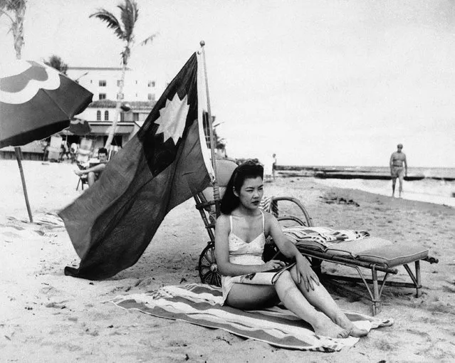 In this December 15, 1941 file photo, Ruth Lee, a hostess at a Chinese restaurant, flies a Chinese flag so she isn't mistaken for Japanese when she sunbathes on her days off in Miami, in the wake of the attack on Pearl Harbor. Lee was born in the U.S. (Photo by AP Photo)