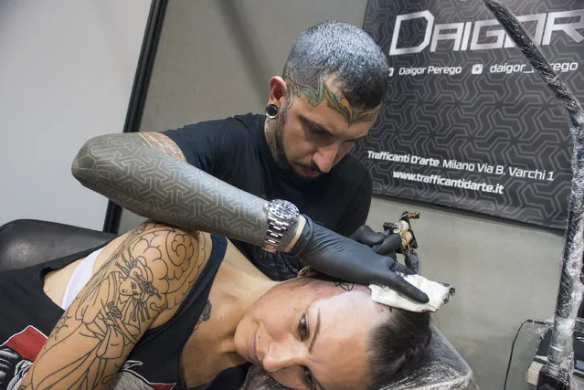 A tattoo artist applys ink on a girl's head at the 2016 Italian Tattoo Artists on September 17, 2016 in Turin, Italy. Italian Tattoo Artists is running from 16 September to 18 September at the Palavela. (Photo by Stefano Guidi/ZUMA Press/Splash News)