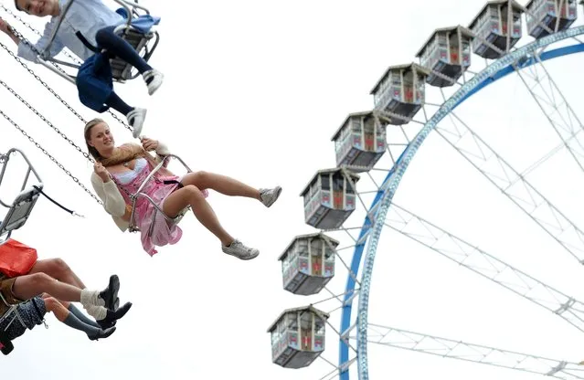 Visitors enjoy a ride on a carosel at the Oktoberfest beer festival in Munich, Germany, 18 September 2016. The 183rd edition of the annual folk and beer festival runs from 17 September to 03 October and is expected to attract once more several millions of visitors from all over the world. (Photo by Andreas Gebert/EPA)