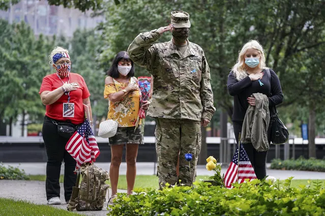 US Army Sgt. Edwin Morales, center right, salutes after places flowers for fallen FDNY firefighter Ruben D. Correa at the National September 11 Memorial and Museum, Friday, Sept. 11, 2020, in New York.  The names of nearly 3,000 victims of the Sept. 11, 2001 terror attacks will be read by family members at a ceremony organized by the Tunnel to Towers Foundation. (Photo by John Minchillo/AP Photo)