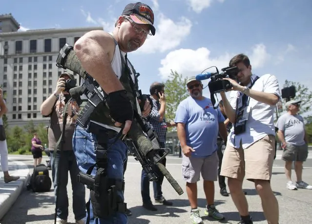 Steve Thacker carrying a rifle and a handgun is surrounded by members of the news media in Cleveland's public square in Cleveland, Ohio, U.S., July 17, 2016. (Photo by Jim Urquhart/Reuters)