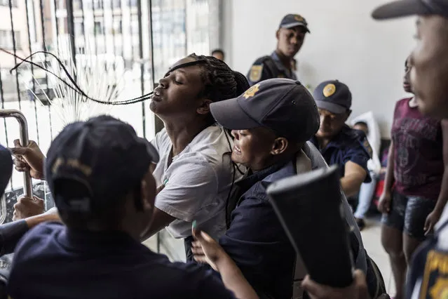 South African Police Services (SAPS) officers detain a woman in the lobby of an apartment block in CBD in Johannesburg, on January 16, 2023 during disturbances with residents following the death of a drug dealer during a police raid. (Photo by Marco Longari/AFP Photo)