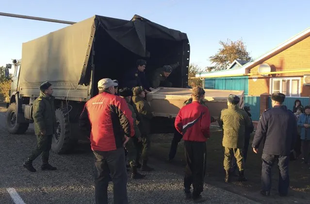 Russian servicemen unload a coffin containing the body of Vadim Kostenko, one of the Russian air force's support staff in Syria, from a truck near his family's house in the village of Grechnaya Balka, north-west of Krasnodar, Russia, October 27, 2015. (Photo by Maria Tsvetkova/Reuters)