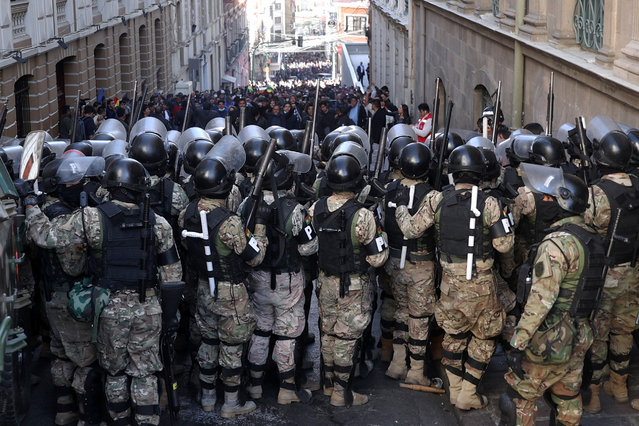 Military police line up in front of supporters of Bolivian President Luis Arce during a protest against military personnel trying to enter the government headquarters in La Paz, Bolivia, 26 June 2024. A group of soldiers led by Bolivian Army general commander Juan Jose Zuniga entered Plaza Murillo on 26 June 2024 using a tank to knock down the door of the government headquarters. The soldiers withdrew after Bolivian President Luis Arce changed the heads of the entire military high command, describing the action as a coup attempt. (Photo by Luis Gandarillas/EPA/EFE)