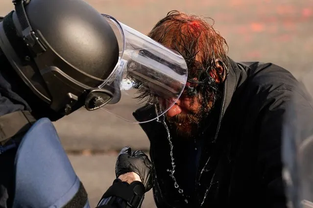 A supporter of President Donald Trump receives aid from law enforcement personnel after clashing with counter-protesters during a rally on December 12, 2020 in Olympia, Washington. (Photo by David Ryder/Getty Images)