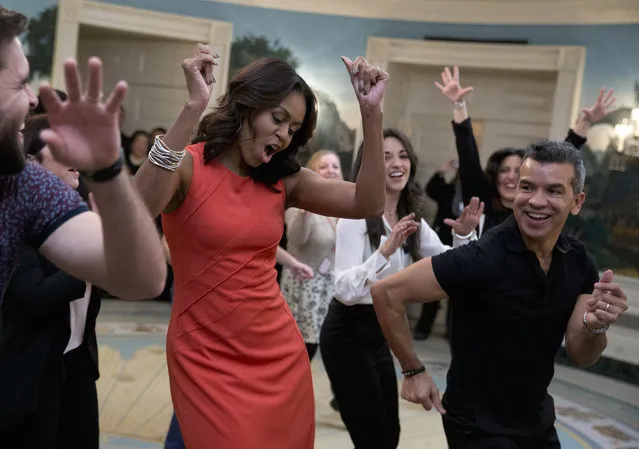 First lady Michelle Obama dances to Gloria Estefan's "Conga" in the Diplomatic Room of the White House in Washington, Monday, November 16, 2015, during a Broadway at the White House event for high school students involved in performing arts programs. She is joined by Sergio Trujillo, Colombian dancer and choreographer, right, and Josh Segarra, left. (Photo by Carolyn Kaster/AP Photo)