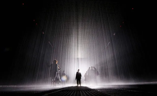 Visitors gather in the new “Rain Room” installation at the Museum of Modern Art (MoMA) in Manhattan, on May 15, 2013. The 5,000 square-foot installation creates a field of falling water that stops in the area where people walk through, allowing them to remain dry. The piece, created by Random International, releases a 260-gallon per minute shower around visitors. (Photo by Mario Tama/Getty Images)