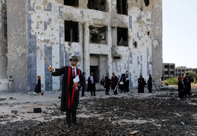 A new graduate of Benghazi University takes a selfie in front of a ruined building at his university former headquarters which was destroyed during clashes in 2014 between members of the Libyan National Army and Shura Council of Libyan Revolutionaries, an alliance of former anti-Gaddafi rebels who have joined forces with Islamist group Ansar al-Sharia, in Benghazi, Libya, October 27, 2016. (Photo by Esam Omran Al-Fetori/Reuters)