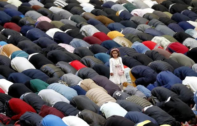 A girl stands and looks aside as worshipers pray while marking Eid al-Fitr at Dinamo Sports Hall, in Bucharest, Romania, 21 April 2023. Muslims around the world are celebrating Eid al-Fitr, the three day festival marking the end of the Muslim holy fasting month of Ramadan. Eid al-Fitr is one of the two major holidays in Islam. (Photo by Robert Ghement/EPA/EFE)