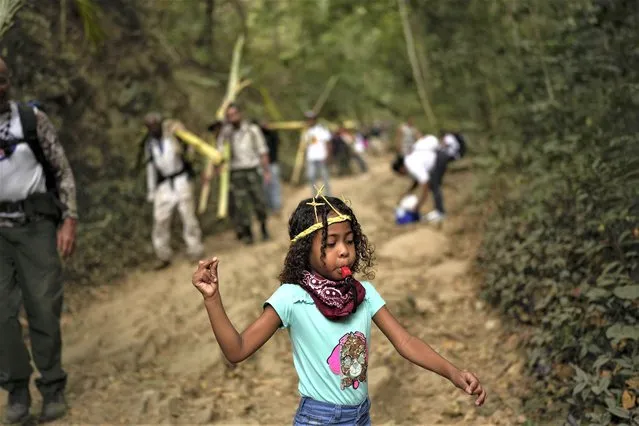 A girl blows a whistle as she descends the Cerro el Avila with members of the Palmeros de Chacao brotherhood, in Caracas, Venezuela, Saturday, April 1, 2023. (Photo by Matias Delacroix/AP Photo)