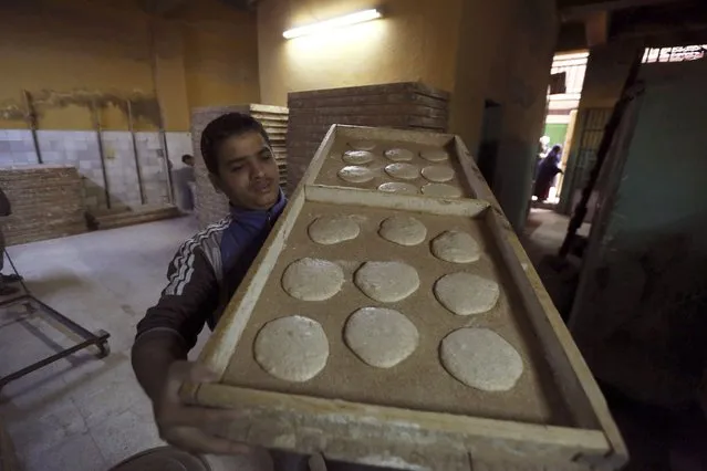 A worker carries dough to be put into an oven in a bakery in Cairo, January 8, 2015. (Photo by Mohamed Abd El Ghany/Reuters)