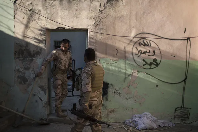 Kurdish Peshmerga soldiers walk next to Islamic State graffiti inside a house in Faziliya, north of Mosul, Iraq, Wednesday, November 2, 2016. (Photo by Felipe Dana/AP Photo)