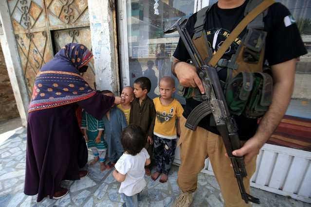 A police officer stand guard as a health worker administers polio vaccine drops to a child during a door-to-door vaccination campaign, in Peshawar, Pakistan, 09 September 2024. A case of poliovirus has emerged in Islamabad after 16 years, marking the total number of cases in Pakistan this year at 17. The eight-year-old boy, from Union Council Rural 4, is the first confirmed case in the capital since 2008. Environmental samples have also tested positive for the virus in 64 districts, highlighting the ongoing threat to children's health. In response, the government has announced a large-scale vaccination campaign set for September 9-13, targeting over 33 million children across 115 districts, including areas with recent cases. Experts have pointed to past mismanagement and the need for a renewed strategy to combat polio, emphasizing the importance of restoring effective leadership and improving vaccination efforts to curb the virus's spread. (Photo by Arshad Arbab/EPA/EFE)