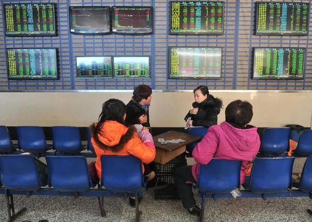 Investors play cards in front of a screen showing stock information at a brokerage house in Hefei, Anhui province, January 19, 2015. (Photo by Reuters/Stringer)