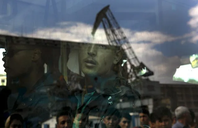 An Afghan migrant is seen through a bus window following his arrival by passenger ferry with over 2,500 migrants and refugees from the island of Lesbos, at the port of Piraeus, near Athens, Greece, October 8, 2015. (Photo by Yannis Behrakis/Reuters)