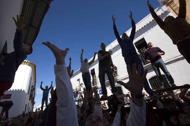 People wait to catch food thrown from balconies during the annual San Antonio Abad (Saint Anton Abbott) festival in Trigueros, southwest Spain January 25, 2015. (Photo by Marcelo del Pozo/Reuters)