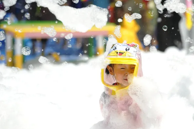 A child plays inside a pool filed with foam bubbles in Huaian, Jiangsu province, China June 23, 2018. (Photo by Reuters/China Stringer Network)