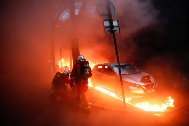 Firefighters work next to a car surrounded by flames during a protest against the “Global Security Bill”, that right groups say would make it a crime to circulate an image of a police officer's face and would infringe journalists' freedom in the country, in Paris, France, December 5, 2020. (Photo by Gonzalo Fuentes/Reuters)