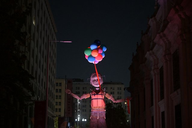 Artists perform during the street Performance “Mo y la Cinta Roja” by l'Homme Debout, during the 32nd version of the International Festival Teatro a Mil, in Santiago, Chile on January 25, 2025. (Photo by Rodrigo Arangua/AFP Photo)