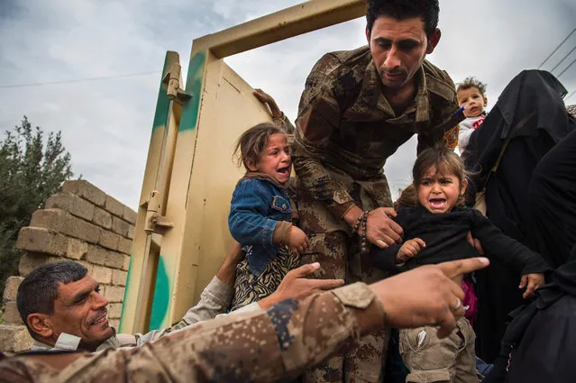 Two Iraqi girls are seen helped onto a truck by Iraqi Special Forces 2nd division soldiers to be transported out of the combat zone in the Samah neighbourhood of Mosul on November 15, 2016 Hundreds of people used the opportunity to get out of harms way during a period of relative calm on the frontline neighbourhoods of eastern Mosul. (Photo by Odd Andersen/AFP Photo)