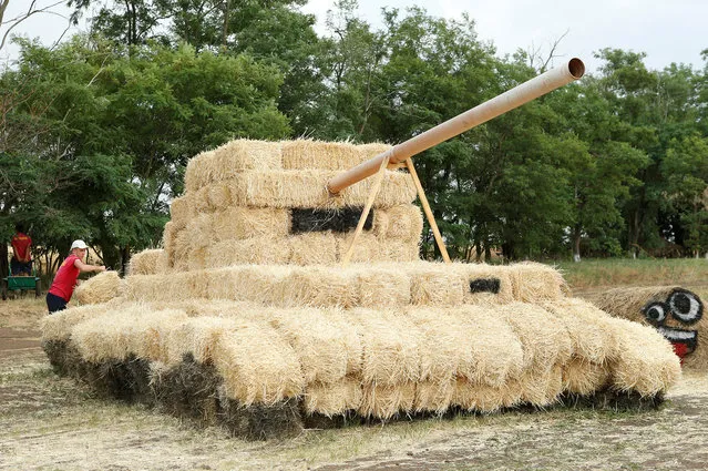 An employee works on an installation at an amusement park, made of straw and erected to attract customers, on the territory of the “Ponomaryovo” farming enterprise in the settlement of Krasnoye in Stavropol Region, Russia July 1, 2018. (Photo by Eduard Korniyenko/Reuters)