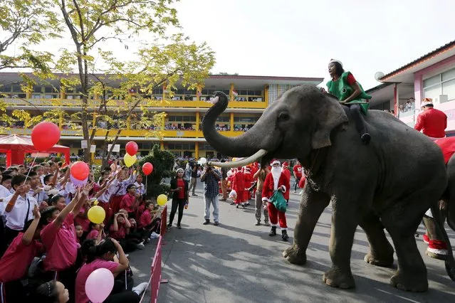 Children receive a puppet thrown by an elephant as they attend a Christmas festival in a primary school in Ayutthaya, Thailand, December 24, 2015. (Photo by Jorge Silva/Reuters)
