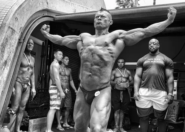 A bodybuilder practices a pose backstage at the Mr. and Mrs. Muscle Beach Competition as a group of wary competitors watch him. Once the home gym of bodybuilders Arnold Schwarzenegger and Lou Ferrigno, the facility still serves the community as an iconic but accessible outdoor weight room. With a yearly membership cost of only $170 and aging gym equipment, the community gym has not yet succumbed to the gentrificationthat surrounds it. (Photo by Dotan Saguy)